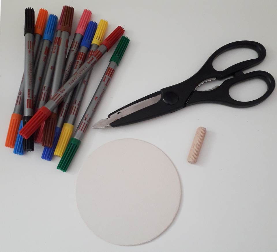Auf der Arbeitsfl&auml;che liegen bunte Filzstifte, eine Schere, ein Holzstab und eine runde, helle Fl&auml;che. Diese Materialien eignen sich f&uuml;r vielf&auml;ltige kreative Experimente und Bastelprojekte im Bildungsbereich.