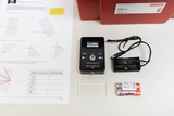 Das Bild zeigt ein Physik-Experimentier-Set zur Lichtbrechung, bestehend aus einem Lasermodul, einer Linse, einem Batteriefach und zwei Batterien. Außerdem ist ein Arbeitsblatt mit Anleitungen zur Durchführung der Experimente abgebildet.