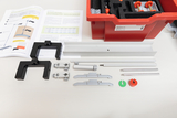 Das Bild zeigt eine Sammlung von Experimentiermaterialien, die für den Physikunterricht verwendet werden können. Neben verschiedenen Halterungen und Stangen sind auch ein Arbeitsheft und eine rote Aufbewahrungsbox sichtbar, die das Zubehör enthält.