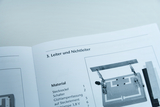 Das Bild zeigt eine Seite eines Handbuchs, das sich mit dem Thema "Leiter und Nichtleiter" beschäftigt. Zusätzlich sind Materialien aufgelistet, darunter Stecksockel, Schalter und eine Glühlampenfassung zur Durchführung von Experimenten.