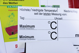 Das Bild zeigt Materialien für die Wetterbeobachtung im Unterricht, einschließlich eines Protokollblattes zur Aufnahme von höchsten und niedrigsten Temperaturen sowie Niederschlag. Im Hintergrund ist ein Arbeitsheft sichtbar, das auf die Lehrerressourcen 