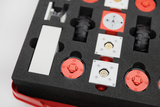 Das Bild zeigt ein Set von Bauteilen, die in einem Schaumstoff-Einsatz organisiert sind, ideal für Experimentierprojekte im Bildungsbereich. Es enthält verschiedene rote und weiße Elemente, darunter Räder und technische Komponenten, die zusammen verwendba