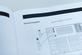 Das Bild zeigt einen Einräumungsplan, der in einem Handbuch abgedruckt ist. Darauf sind verschiedene Materialien und deren Anordnung dargestellt, vermutlich für den Einsatz in Experimenten im Bildungsbereich.