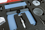 Das Bild zeigt eine aufgeschlossene Schaumstoffbox, die verschiedene Teile für einen Experimentierbedarf enthält. Zu den Komponenten gehören eine Zündkerze, ein Halteblech und diverse Metallteile, die wahrscheinlich für physikalische Experimente verwendet werden.