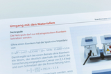 Das Bild zeigt eine Anleitung zum Umgang mit einer Netzspule, die nur mit einem Eisenkern betrieben werden darf. Es enthält außerdem technische Informationen zur Impedanz und Sicherheitshinweise für den Einsatz der Spule in Experimenten.