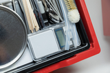 Das Bild zeigt einen gut organisierten Experimentierkasten mit verschiedenen Materialien, wie Messgeräten, Löffeln, Stäbchen und Bürsten. Diese Utensilien sind für die Durchführung von wissenschaftlichen Experimenten im Bildungsbereich konzipiert.