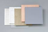 Das Bild zeigt eine Ansammlung von verschiedenen Materialien, darunter Holz, Metall und Kunststoff, die in quadratischen Plattenformaten angeordnet sind. Diese Platten sind wahrscheinlich für experimentelle Zwecke im Bildungswesen gedacht.