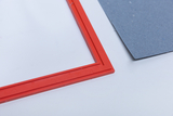 Das Bild zeigt einen roten Rahmen mit einem transparenten Netz und ein graues Blatt Papier daneben. Diese Gegenstände können für verschiedene Bildungs-Experimente verwendet werden, um physikalische oder chemische Phänomene zu veranschaulichen.
