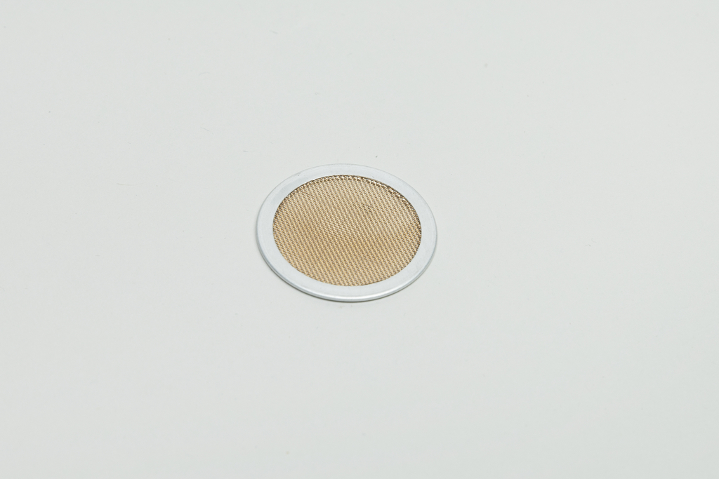 Das Bild zeigt einen runden Metallfilter mit einem klaren Rand und einem feinmaschigen, bronzefarbenen Netz in der Mitte. Er wird wahrscheinlich in chemischen Experimenten oder für die Filtration von Flüssigkeiten verwendet.