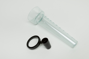 Das Bild zeigt ein transparentes Messzylinder mit Skala, ideal für Experimentierzwecke. Neben dem Zylinder liegt ein schwarzer, runder Halter, möglicherweise für eine Lupe oder ähnliches Zubehör.