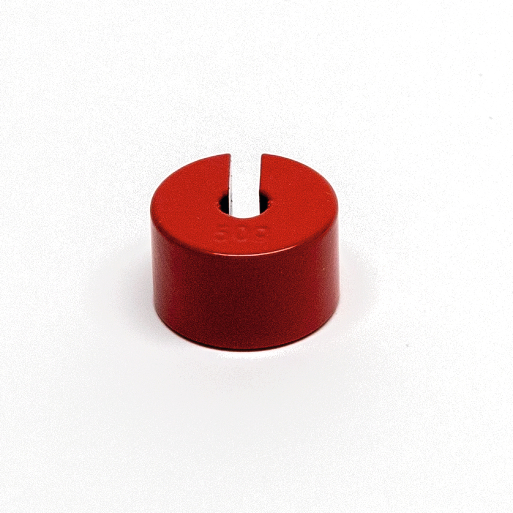 Das Bild zeigt einen roten Zylinder mit einer Schlitzöffnung an der Oberseite, der vermutlich als Gewicht oder Halterung in experimentellen Anwendungen verwendet wird. Mit einer gravierten Gewichtsanzeige von 50 g eignet er sich gut für den Einsatz im Bildungsbereich.