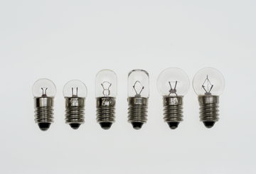 Das Bild zeigt eine Reihe von Glühbirnen unterschiedlicher Größen, die in einer klaren Anordnung nebeneinander platziert sind. Jede Birne hat eine Metallbasis und ist teilweise transparent, sodass die Innenstruktur sichtbar ist.