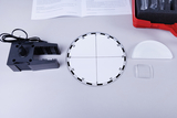 Das Bild zeigt eine Sammlung von Experimentiermaterialien, darunter einen mechanischen Halter, eine runde Skala mit Graduierungen, sowie verschiedene optische Elemente wie Linsen. Diese Materialien sind für den Einsatz in Bildungsprojekten konzipiert, um physikalische Phänomene zu untersuchen.