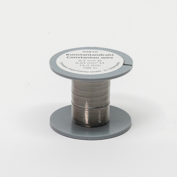 Das Bild zeigt eine Rolle Konstantandraht mit einer Länge von 100 Metern. Der Draht hat einen Durchmesser von 0,2 mm und eine spezifische Widerstand von 15,4 Ω/m, geeignet für verschiedene experimentelle Anwendungen im Bildungsbereich.