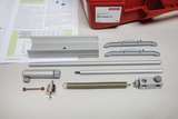 Das Bild zeigt verschiedene Komponenten eines Experimentierkästs zum Thema Mechanik, einschließlich Metall- und Kunststoffteilen sowie einer Anleitung mit Diagrammen und Formeln. Diese Bestandteile sind darauf ausgelegt, Schülern das Verständnis physikalischer Konzepte zu erleichtern.