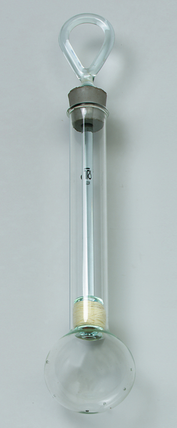 Das Bild zeigt einen Experimentierglasartikel, der aus einem langgestreckten Glasrohr mit einer halbkugelförmigen Basis besteht. Oben hat es einen geschlossenen Hals, der eine Aufhängemöglichkeit bietet, und im Inneren sind Materialien sichtbar, die für chemische Experimente genutzt werden können.
