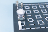 Das Bild zeigt ein Experimentierboard mit verschiedenen Anschlussmöglichkeiten, das für technische Schulprojekte verwendet werden kann. Die Anordnung und die metallischen Anschlüsse sind ideal, um elektrische Schaltkreise zu erstellen und Experimentieraufbauten zu ermöglichen.