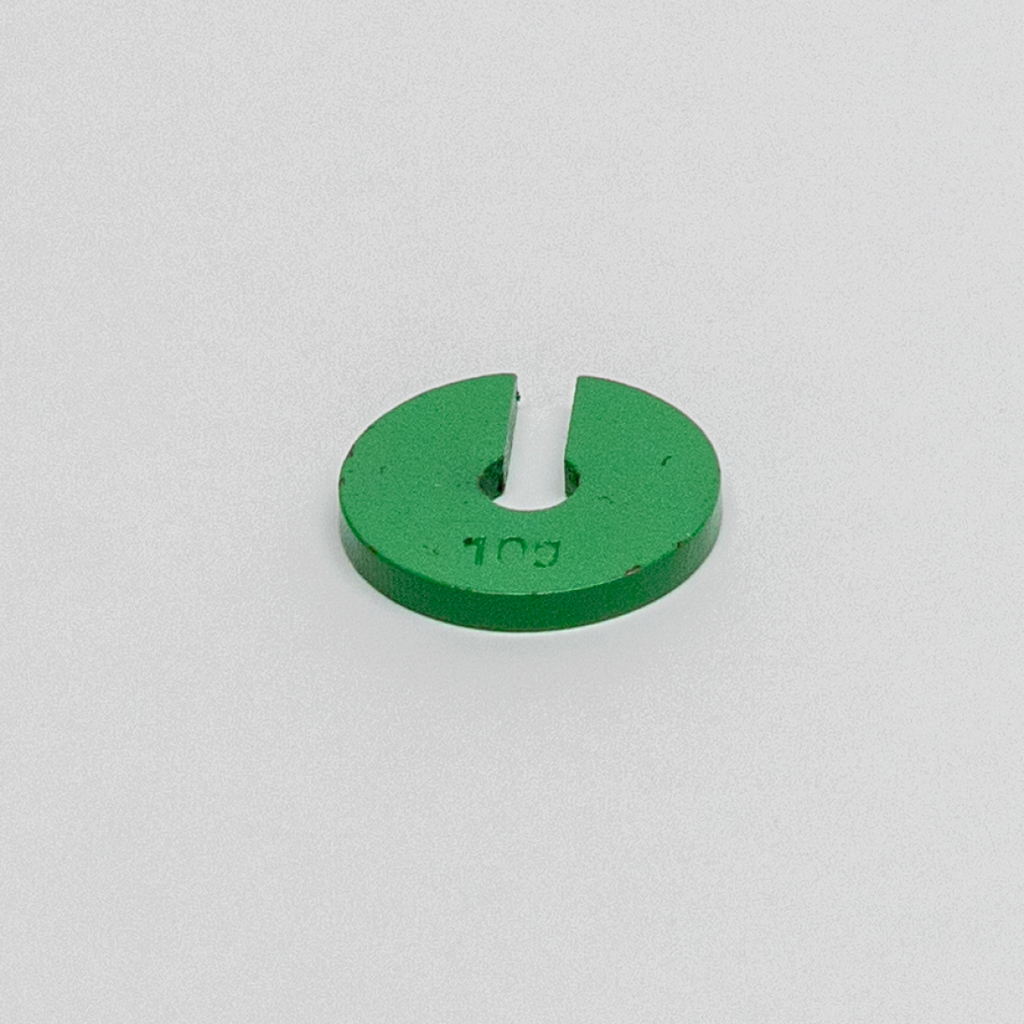 Das Bild zeigt eine grüne, runde Kunststoffscheibe mit einer Einkerbung in der Mitte. Diese Scheibe könnte als Experimentiermaterial im Bildungswesen verwendet werden, möglicherweise zur Durchführung von Versuchen oder zur Unterstützung bestimmter physikalischer Aufgaben.