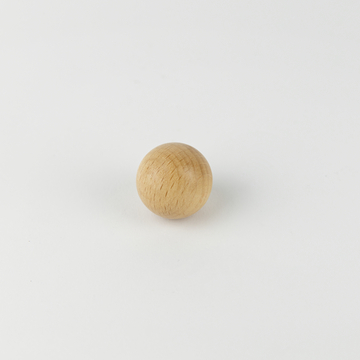 Auf dem Bild ist eine kleine, runde Holzkugel zu sehen, die auf einer weißen Fläche liegt. Sie könnte als Experimentiermaterial oder Spielzeug verwendet werden und dient möglicherweise zur Unterstützung im Bildungswesen.