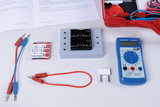 Das Bild zeigt eine Sammlung von Experimentiermaterialien, darunter Batterien, ein Multimeter und verschiedene Verbindungskabel. Diese Ausrüstung ist für Bildungszwecke in naturwissenschaftlichen Experimenten konzipiert.