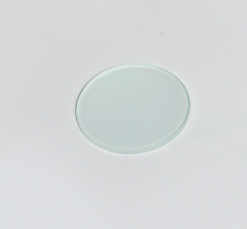 Das Bild zeigt eine durchsichtige, runde Objektträgerplatte aus Glas, die auf einem weißen Untergrund liegt. Diese Platte wird häufig in wissenschaftlichen Experimenten und bei mikroskopischen Untersuchungen verwendet.