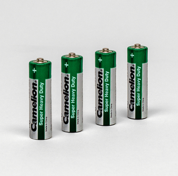 Das Bild zeigt vier grüne Batterien der Marke Camelion mit der Aufschrift "Super Heavy Duty". Sie sind nebeneinander auf einem weißen Hintergrund angeordnet.