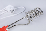 Das Bild zeigt einen elektrischen Heizstab aus Edelstahl, der zum Erhitzen von Flüssigkeiten verwendet wird. Er ist mit einem weißen Stromkabel und einem Stecker ausgestattet, der für den Einsatz im Bildungsbereich geeignet ist.