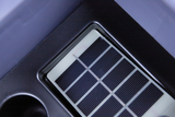 Das Bild zeigt eine Solarzelle, die in eine graue Halterung eingelassen ist. Sie besteht aus mehrere parallele, schwarz gefärbte Streifen, die zur Nutzung von Sonnenenergie dienen.