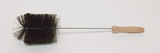 Das Bild zeigt eine große, schwarze Reinigungsbürste mit einem langen Metallgriff und einem Holzgriff. Sie ist möglicherweise für den Einsatz in Experimenten oder im Bildungsbereich gedacht, um Materialien zu reinigen oder zu bearbeiten.