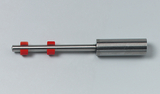 Das Bild zeigt ein Experimentiergerät aus Metall mit einer glatten Oberfläche und zwei roten Kunststoffringen. Es könnte sich um ein Werkzeug für physikalische Experimente oder Demonstrationen handeln.