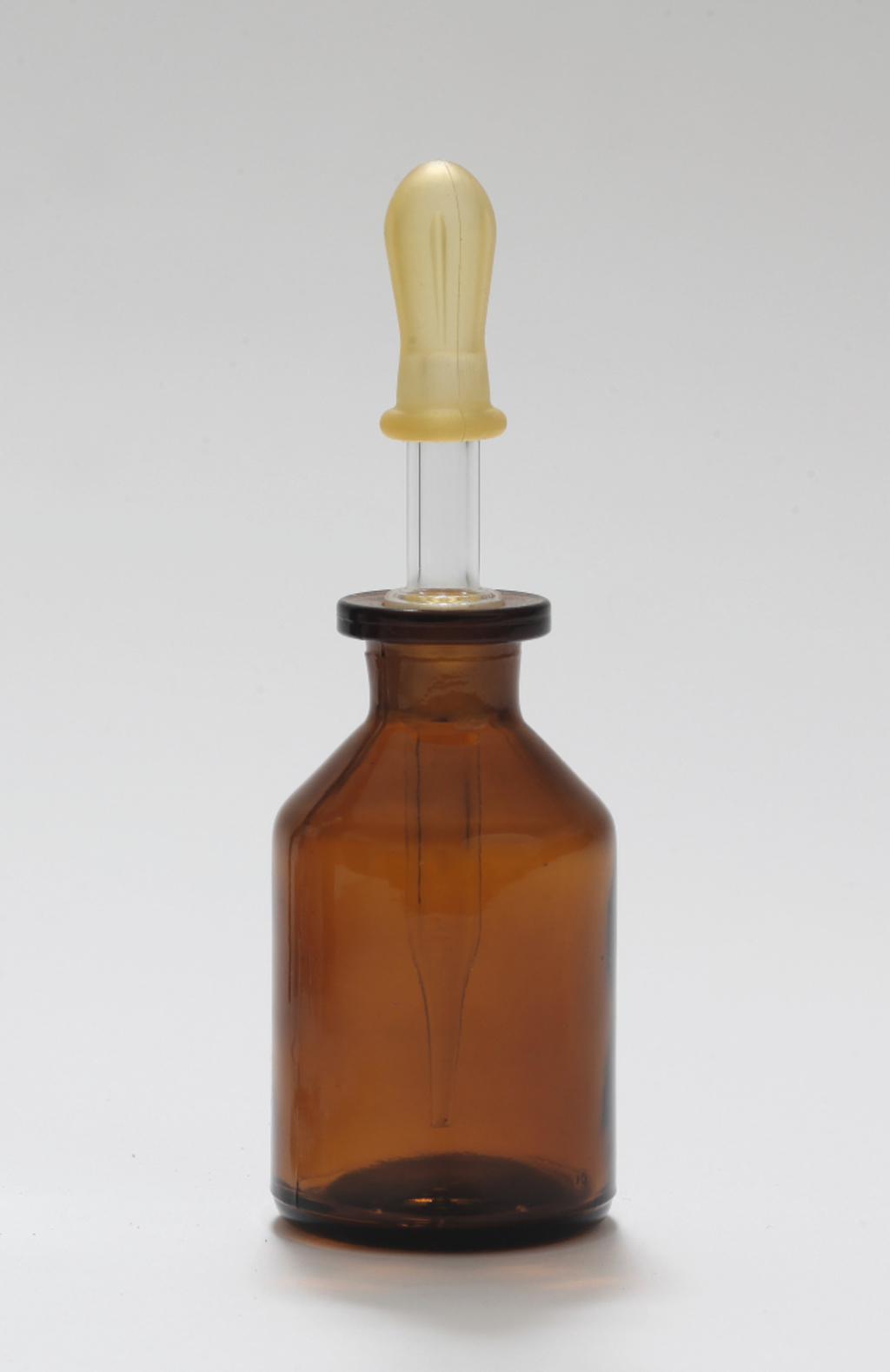Das Bild zeigt eine braune Glasflasche mit einem Gummiversiegeler, der einen langen Glasröhrchen enthält. Diese Kombination dient wahrscheinlich zur präzisen Dosierung von Flüssigkeiten im experimentellen Bereich.