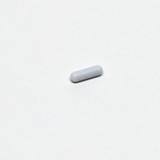 Das Bild zeigt eine kleine, weiße, längliche Pille oder Tablette, die auf einem weißen Hintergrund liegt. Sie scheint ein Experimentiermaterial zu sein, das möglicherweise in wissenschaftlichen oder educational Kontexten verwendet wird.
