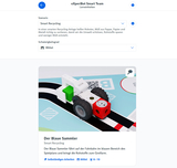 Ein Roboterfahrzeug namens "Der Blaue Sammler" ist auf einer Spielbahn abgebildet und hat die Aufgabe, verschiedene Rohstoffe wie Papier und Metall zu sammeln. Es ist Teil eines didaktischen Szenarios zum Thema Recycling für innovative Bildungsprogramme.