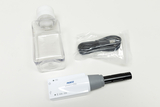Ein drahtloser CO2-Sensor von PASCO liegt neben einer leeren Kunststoffflasche. Ein verpacktes USB-Ladekabel ergänzt das Set für wissenschaftliche Experimente.