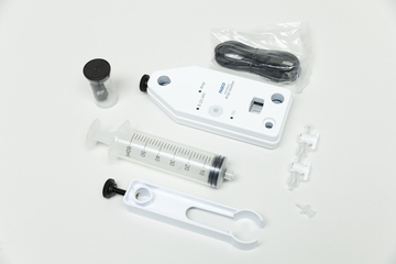 Ein Set bestehend aus einem digitalen Tropfenzähler, einer Spritze und einem Halter liegt auf weißem Grund. Ergänzt wird das Equipment durch ein USB-Kabel und kleine Kunststoffzubehörteile.