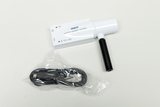 Ein weißer, kabelloser Geigerzähler der Marke PASCO liegt auf einer hellen Fläche. Daneben befindet sich ein in Kunststoff verpacktes USB-Ladekabel.