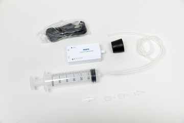 Ein PASCO-Drucksensor mit USB-Kabel, einem Kunststoffschlauch und einer Spritze liegt auf weißem Grund. Ergänzt wird das Set durch kleine Kunststoffadapter für Experimente im Physikunterricht.