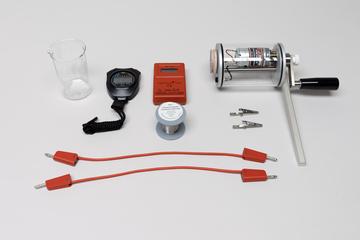 Ein Set aus physikalischen Experimentiergeräten umfasst einen Dynamo, ein Messgerät sowie Zubehör. Ergänzt wird die Ausstattung durch ein Becherglas, Anschlusskabel und eine Drahtspule.