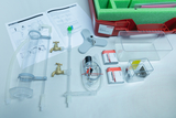 Ein Set für physikalische oder chemische Experimente mit Wasserleitungen, Hähnen und Behältnissen liegt bereit. Ergänzt wird das Equipment durch eine Anleitung und eine rote Aufbewahrungsbox.