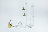 Ein physikalischer Versuchsaufbau zeigt eine durchsichtige Säule mit zwei Messinghähnen und einer Wasserwanne. Ein angeschlossenes Stromgerät dient vermutlich zur Demonstration von Druck- oder Flüssigkeitsprinzipien.