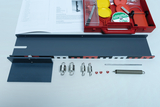 Ein Physik-Experimentierkasten liegt geöffnet auf einer weißen Fläche. Neben einer Anleitung befinden sich Federn, eine Schiene sowie diverse Zubehörteile in einer roten Kunststoffbox.