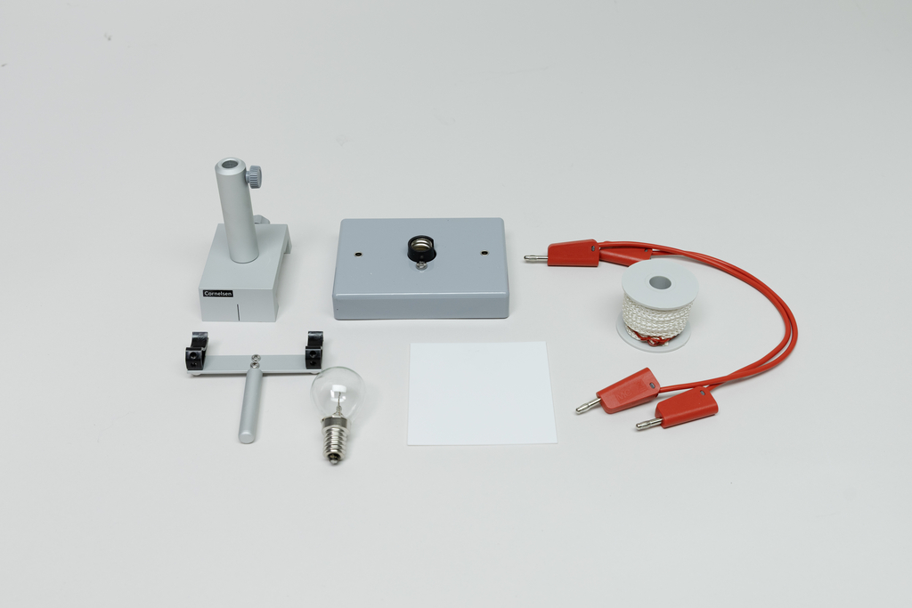 Ein Physik-Experimentierset besteht aus einer Glühbirne, einer Stromquelle, Verbindungskabeln und einer Halterung. Ergänzt wird das Set durch eine weiße Fläche sowie weitere Montageelemente auf weißem Hintergrund.
