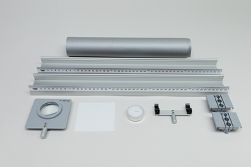 Ein Set aus optischen Experimentiergeräten liegt auf einer hellen Fläche. Es umfasst eine optische Bank mit Linealen, eine Linse, einen Spiegel sowie diverse Halterungen und Zubehör.