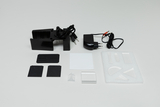 Ein Set aus physikalischen Experimentierutensilien liegt auf einer weißen Fläche. Es umfasst eine Stromquelle mit Adapter sowie diverse Lichtfilter- und Prismenelemente.