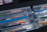 Mehrere transparente Kunststoffboxen enthalten verschiedenfarbige Karten und Streifen. Diese sind systematisch in einem schwarzen Schaumstoffeinsatz sortiert.